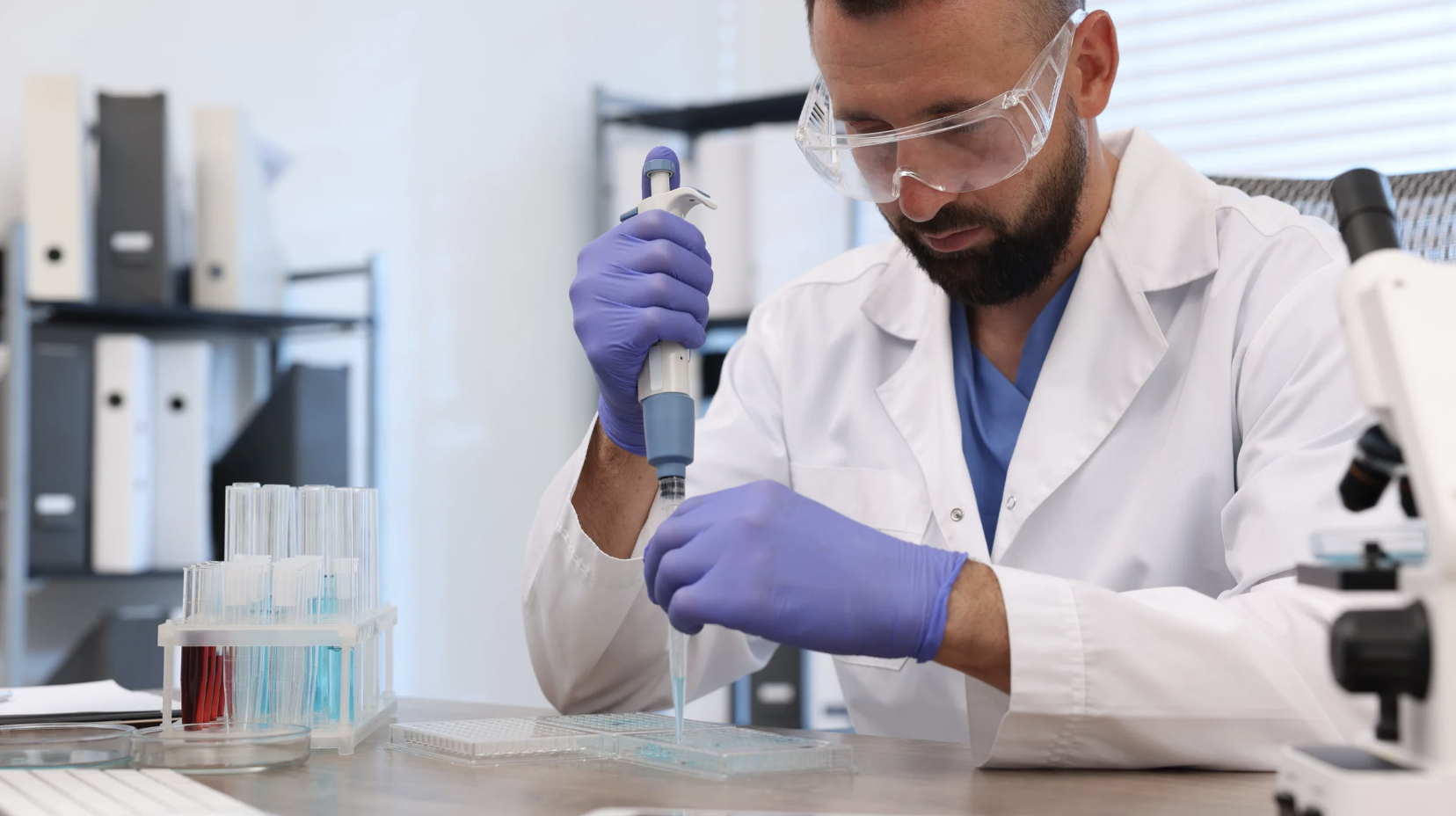 Researcher conducting laboratory analysis of research peptide compounds in test tubes using pipette equipment in professional biomedical research facility